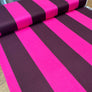 A roll of fabric with bold, alternating bright pink and dark plum purple stripes, partially unrolled to show its texture and pattern.